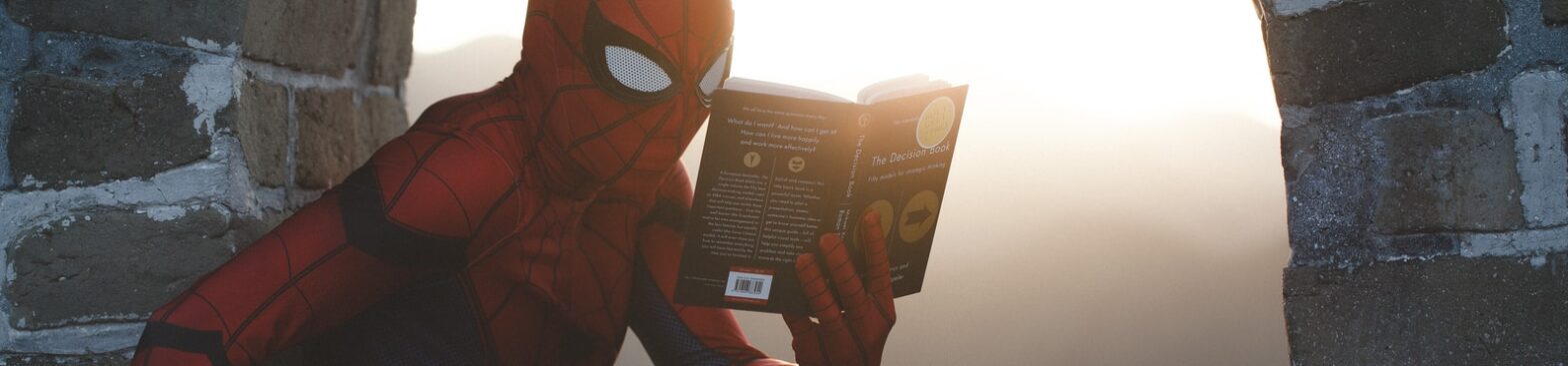 Spider-Man leaning on concrete brick while reading book